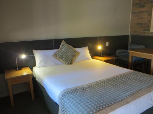 a bedroom with a large bed with two lamps on tables at Cattleman's Rest Motor Inn in Charters Towers