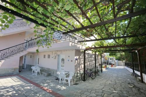 een gebouw met een tafel, stoelen en bomen bij Theramvos Superior Apartments in Hanioti