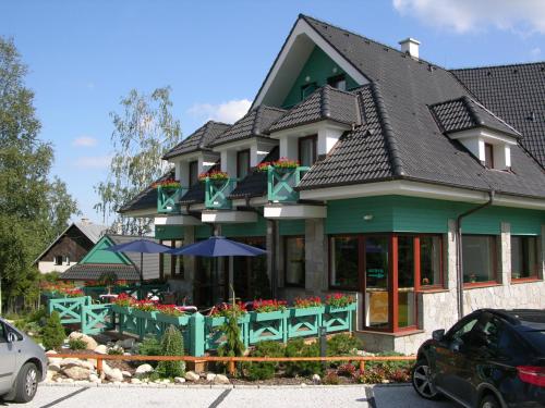 a green building with flowers in front of it at Penzión Paula in Tatranská Lomnica