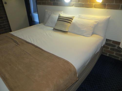 a large bed with white sheets and pillows at Cattleman's Rest Motor Inn in Charters Towers