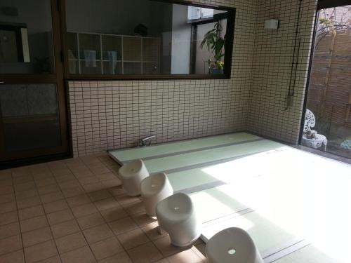 a bathroom with a tub and toilets in a room at Hotel Wakasato in Nagano