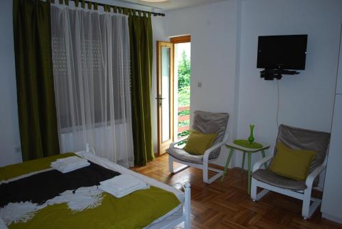 a bedroom with a bed and two chairs and a tv at Guest House Ozon in Soko Banja