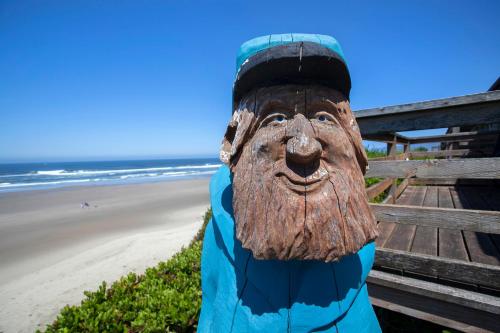 a statue of a wooden head sitting on a bench at the beach at Moolack Shores Inn in Newport