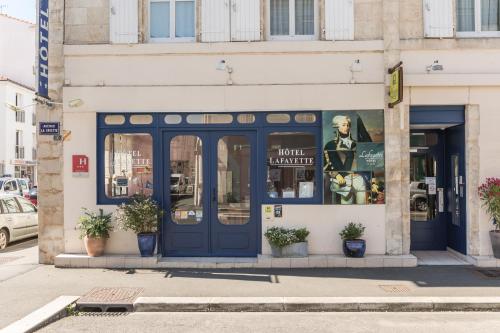 a store front with blue doors on a city street at Logis Hôtel Lafayette Rochefort France in Rochefort