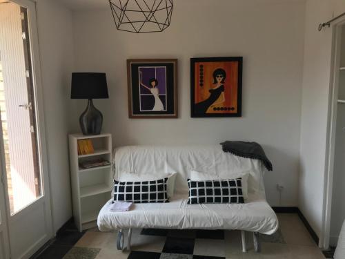 un canapé blanc dans un salon avec des tableaux au mur dans l'établissement La Villersoise - Grand studio 4 personnes, à Villers-sur-Mer