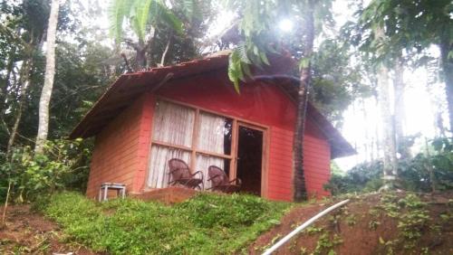 a small red house with a window on a hill at Edgestay in Mudigere