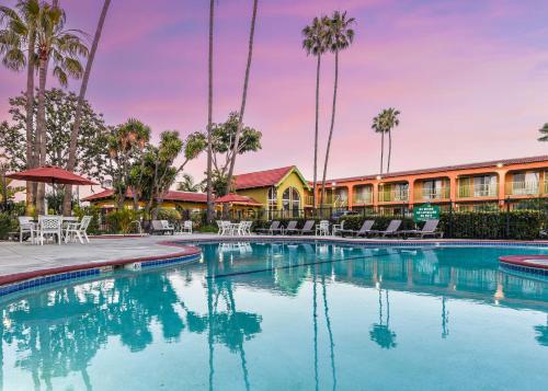 a pool at a resort with chairs and palm trees at Vagabond Inn Costa Mesa in Costa Mesa