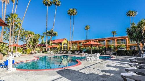 a resort with a pool and chairs and palm trees at Vagabond Inn Costa Mesa in Costa Mesa