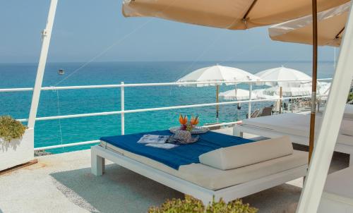 a table on a balcony with an umbrella and the ocean at Hotel La Roccia in Castro di Lecce