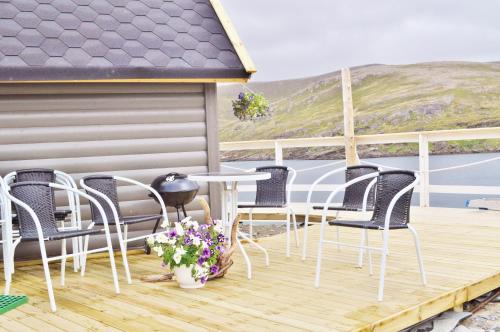 a patio with chairs and a table on a deck at Cape Marina Lodge in Skarsvåg