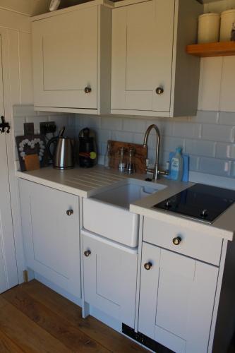 a kitchen with white cabinets and a sink at Fair Farm Hideaway in Waltham on the Wolds