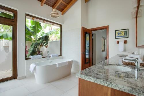 ein Badezimmer mit einer großen weißen Badewanne und einem Waschbecken in der Unterkunft Naïa Resort and Spa in Placencia Village