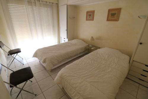 une chambre avec deux lits, un bureau et une chaise dans l'établissement 2 bedroom, 2 bathrooms, 2 mins from the Croisette, Monod 348, à Cannes