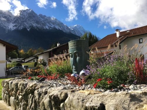 a stone retaining wall with a statue of a face in a garden at Ferienhaus Alpenperle in Grainau