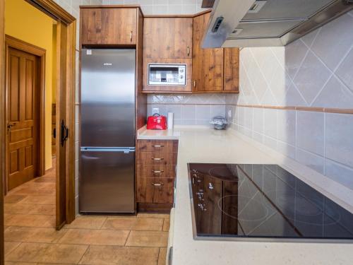 a kitchen with a stainless steel refrigerator and wooden cabinets at Casa Rural El Serrano in Prioro