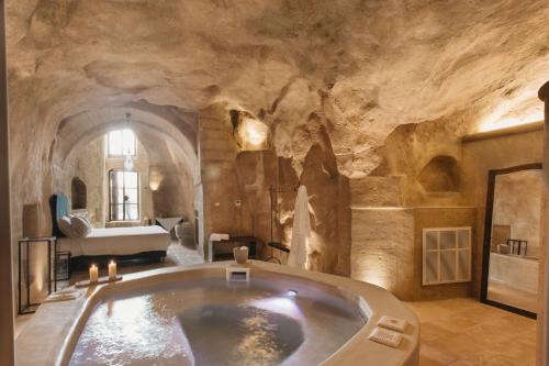 La grande salle de bains est pourvue d'une baignoire dans un mur en pierre. dans l'établissement Palazzo Del Duca Hotel & Restaurant, à Matera