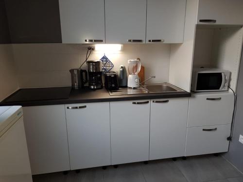 une petite cuisine avec des armoires blanches et un micro-ondes dans l'établissement Hameau des Essarts, à Grand-Couronne