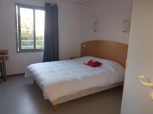 Un dormitorio con una cama con una almohada roja. en Au Périgord Noir, en Hautefort