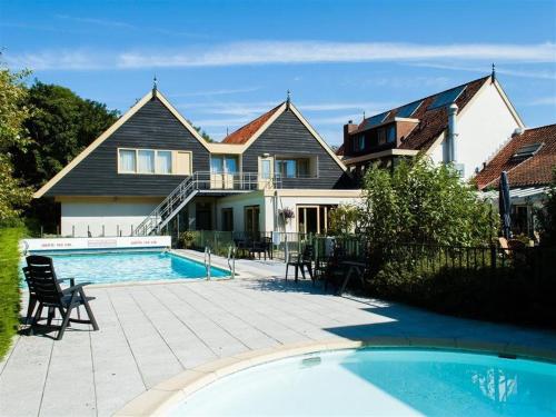 a house with a swimming pool in front of a house at Ferienwohnung Westerlicht - Apartment am Leuchtturm - De Torenhoeve in Nieuw-Haamstede
