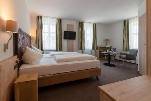 a hotel room with a large bed and a desk at Gasthof & Hotel Goldene Krone in Iphofen