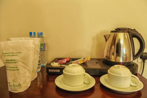 a table with two cups and a tea kettle at Oak Ray Tea Bush in Ramboda