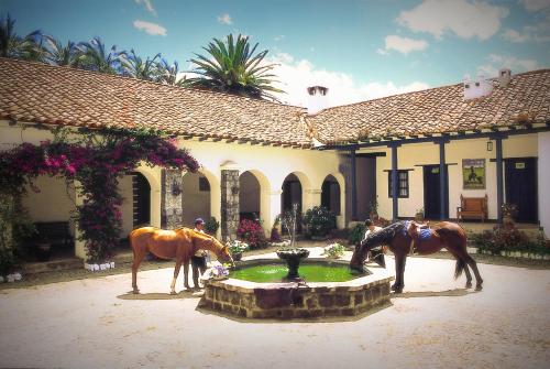 two horses standing around a fountain in front of a building at Hostería Hacienda Pinsaqui in Otavalo