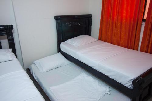 two twin beds in a room with red curtains at El Velero Apartamentos By DANP in Santa Marta