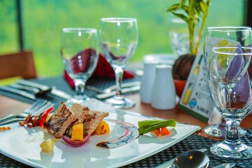 a plate of food on a table with wine glasses at Oak Ray Tea Bush in Ramboda
