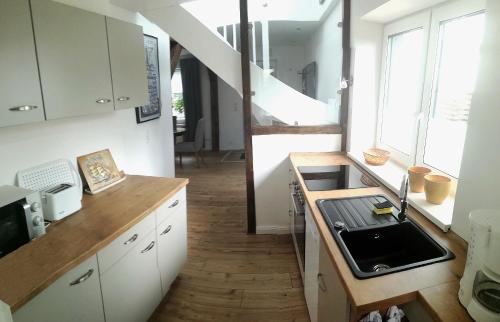uma cozinha com armários brancos, um lavatório e uma escadaria em Ferienhaus Schleeff em Elsfleth