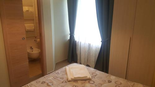 een badkamer met een bed, een wastafel en een raam bij Le terme a due passi in Rapolano Terme
