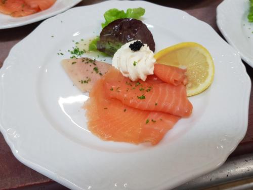 a plate of food with fish and a lemon at Hotel zur Waage in Bad Münstereifel