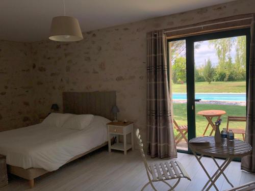 1 dormitorio con cama, mesa y ventana en FERME DE L'EREAU, en Louans