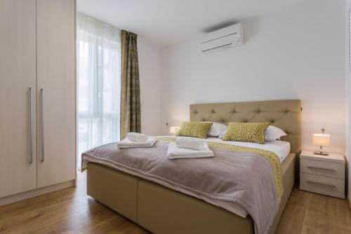 een slaapkamer met een groot bed en handdoeken bij Pure Relax in Malinska