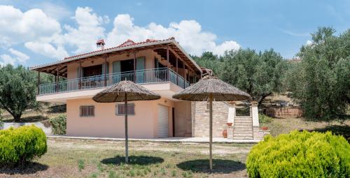 a house with a balcony and two umbrellas at Villa Artjeta in Kastrosikia