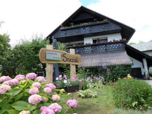 a sign in front of a house with flowers at Snežak (Snowman) in Bohinj