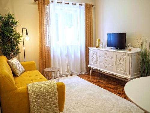a living room with a yellow couch and a television at Viana Lovers in Viana do Castelo