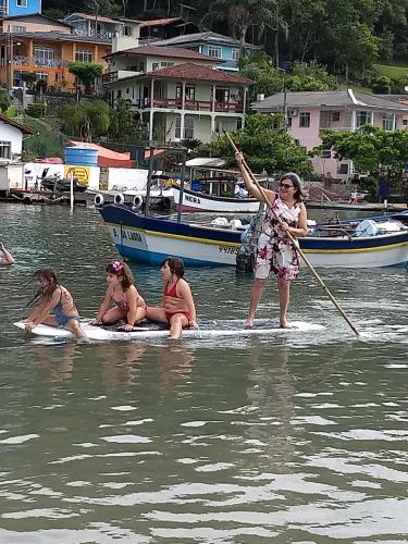 un grupo de chicas en una tabla de surf de remo en el agua en Residencial Lena a 300 metros da praia, en Florianópolis