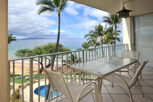 a balcony with a table and chairs and the ocean at The Hale Pau Hana in Kihei