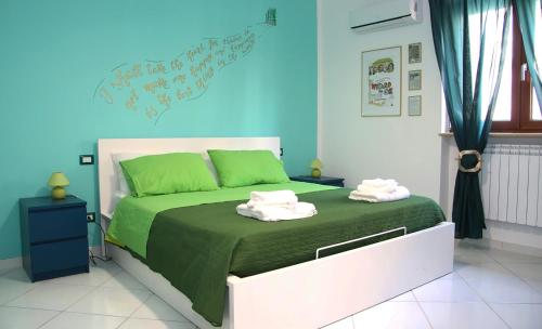 una camera da letto con un letto verde e bianco con asciugamani di MarArte B&B a Trecase
