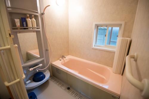 een badkamer met een bad, een wastafel en een spiegel bij Guest House Wagaranchi Kai in Kumano