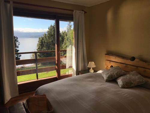 a bedroom with a bed and a large window at Las Juntas Ecolodge in Puyehue