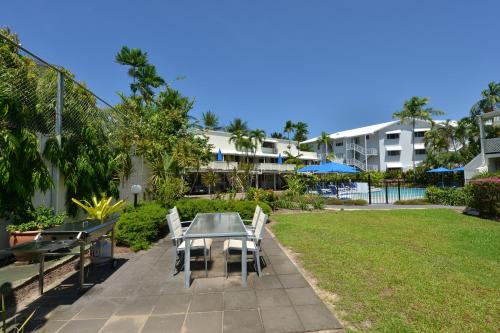 a patio with a table and chairs and a building at Seascape Holidays at Beachfront Terraces in Port Douglas