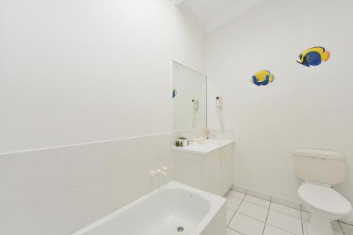 a white bathroom with a toilet and a sink at Seascape Holidays at Beachfront Terraces in Port Douglas
