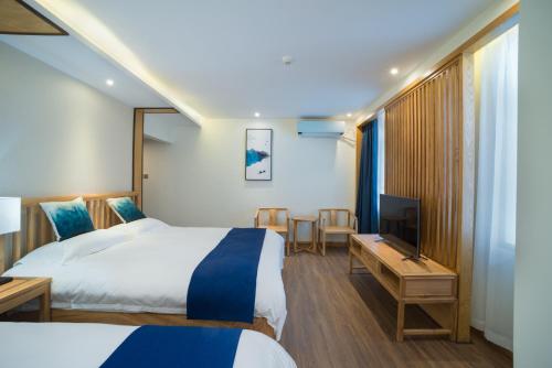 a hotel room with two beds and a flat screen tv at Riverside Inn Guilin Central in Guilin