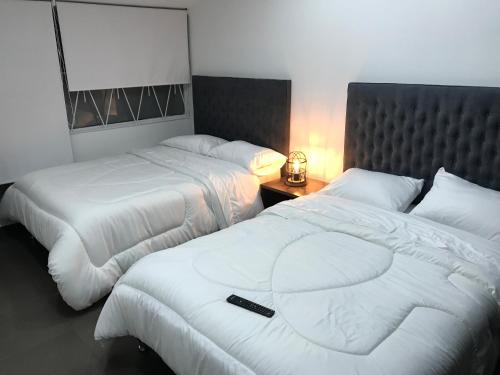 a hotel room with two beds with a remote control on it at Hotel OrangeTrip in Bogotá
