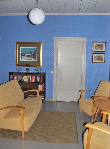 a living room with blue walls and a couch and chairs at Kirjakkalan Ruukkikylä in Teijo
