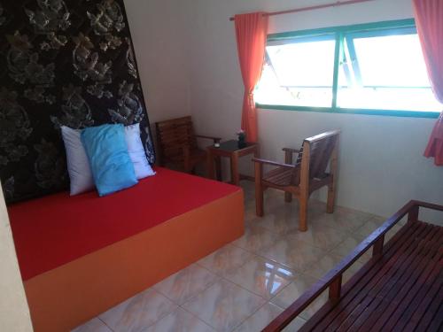 a bedroom with a bed and chairs and a window at pulau weh sabang marifi in Paya