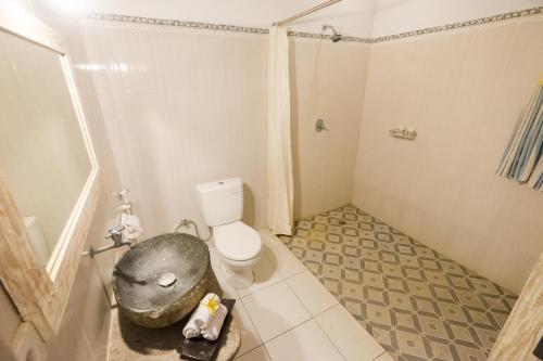 a bathroom with a toilet and a bath tub at Kubu Betel Home Stay in Canggu
