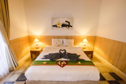 a bedroom with a bed with two robes on it at Kubu Betel Home Stay in Canggu