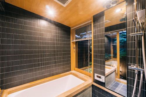 京都市にある美盧八条源町邸の黒いタイル張りのバスルーム(バスタブ付)